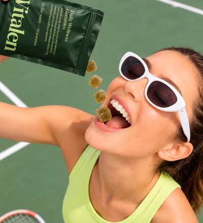 A woman in sunglasses catching gummies poured from a Vitalen pouch